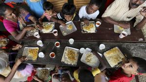 A group of flood affected people, mostly children, sit together to have a meal at a relief camp set up inside a school in Kochi.(AP Photo) A group of flood affected people, mostly children, sit together to have a meal at a relief camp set up inside a school in Kochi.(AP Photo)