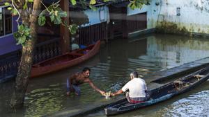A man standing in floodwater shares a tray of tea with another man sitting in a canoe in Kainakary village in the district of Alappuzha, Kerala.(Bloomberg Photo) A man standing in floodwater shares a tray of tea with another man sitting in a canoe in Kainakary village in the district of Alappuzha, Kerala.(Bloomberg Photo)