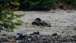 A damaged vehicle lies amidst a swollen Beas river flows after heavy rains in the region, in Kullu district, on Monday.(PTI) A damaged vehicle lies amidst a swollen Beas river flows after heavy rains in the region, in Kullu district, on Monday.(PTI)