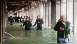 Tourists under arches next to the flooded St Mark's Square during a high-water (Acqua Alta) alert in Venice on October 29.(AFP Photo) Tourists under arches next to the flooded St Mark's Square during a high-water (Acqua Alta) alert in Venice on October 29.(AFP Photo)