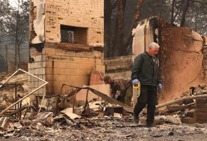 A Butte County sherriff deputy searches the property of a destroyed home for a reported Camp Fire victim in Paradise, California. Fueled by high winds and low humidity, the rapidly spreading Camp Fire ripped through the town of Paradise and has quickly charred 100,000 acres and has destroyed over 6,700 homes and businesses in a matter of hours.(AFP) A Butte County sherriff deputy searches the property of a destroyed home for a reported Camp Fire victim in Paradise, California. Fueled by high winds and low humidity, the rapidly spreading Camp Fire ripped through the town of Paradise and has quickly charred 100,000 acres and has destroyed over 6,700 homes and businesses in a matter of hours.(AFP)
