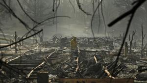 A firefighter searches for human remains in a trailer park destroyed in the Camp Fire, in Paradise, California. The massive wildfire that killed dozens of people and destroyed thousands of homes has been fully contained after burning for more than two weeks.(AP) A firefighter searches for human remains in a trailer park destroyed in the Camp Fire, in Paradise, California. The massive wildfire that killed dozens of people and destroyed thousands of homes has been fully contained after burning for more than two weeks.(AP)