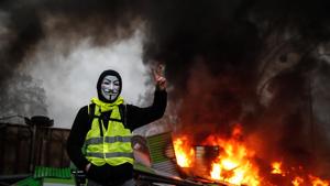 A protester wearing a Guy Fawkes mask makes the victory sign near a burning barricade during a protest of Yellow vests (Gilets jaunes) against rising oil prices and living costs, on December 1, 2018 in Paris.(AFP) A protester wearing a Guy Fawkes mask makes the victory sign near a burning barricade during a protest of Yellow vests (Gilets jaunes) against rising oil prices and living costs, on December 1, 2018 in Paris.(AFP)
