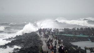 People walk along a breakwater at Kasimedu fishing harbour as Cyclone Phethai approaches Chennai on Sunday.(AFP Photo) People walk along a breakwater at Kasimedu fishing harbour as Cyclone Phethai approaches Chennai on Sunday.(AFP Photo)