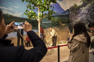 Visitors take photographs of a diorama of China's former leader Deng Xiaoping planting a tree in the Visitors take photographs of a diorama of China's former leader Deng Xiaoping planting a tree in the