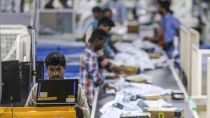 An employee uses a laptop computer while packages move along a conveyor belt at the Amazon.com Inc. fulfillment center in Hyderabad.(Bloomberg) An employee uses a laptop computer while packages move along a conveyor belt at the Amazon.com Inc. fulfillment center in Hyderabad.(Bloomberg)