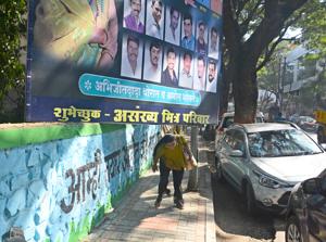 Pedestrians bend down to walk on a footpath as an illegal hoarding encroached the footpath on Dhole Patil road.(Shankar Narayan/HT PHOTO) Pedestrians bend down to walk on a footpath as an illegal hoarding encroached the footpath on Dhole Patil road.(Shankar Narayan/HT PHOTO)