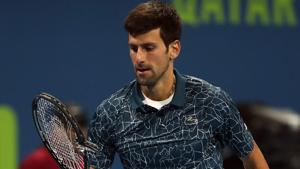 Novak Djokovic of Serbia reacts as he holds his broken racquet during his Qatar Open semi-final match.(AFP)