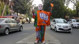 A supporter of Bharatiya Janata Party (BJP) wears a mask depicting Prime Minister Narendra Modi, and drapes himself with flags of BJP's symbol at a traffic signal in Bhopal.(REUTERS) A supporter of Bharatiya Janata Party (BJP) wears a mask depicting Prime Minister Narendra Modi, and drapes himself with flags of BJP's symbol at a traffic signal in Bhopal.(REUTERS)
