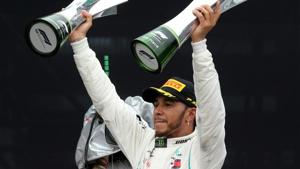 Mercedes' Lewis Hamilton celebrates after winning the race with the constructors championship trophy and the race trophy.(REUTERS) Mercedes' Lewis Hamilton celebrates after winning the race with the constructors championship trophy and the race trophy.(REUTERS)