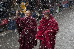 A Tibetan Buddhist monk uses his phone camera as he walks with another in the snow in Dharmsala, February 27, 2019.(AP) A Tibetan Buddhist monk uses his phone camera as he walks with another in the snow in Dharmsala, February 27, 2019.(AP)