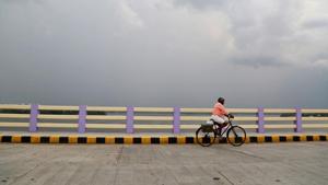 A man rides his bicycle across a bridge as pre-monsoon clouds gather over the Vembanad Lake in Kochi on May 8, 2018.(REUTERS) A man rides his bicycle across a bridge as pre-monsoon clouds gather over the Vembanad Lake in Kochi on May 8, 2018.(REUTERS)
