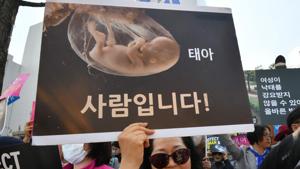 A South Korean pro-lifer holds a placard showing an image of embryo during a rally supporting an abortion ban outside the constitutional court in Seoul.(AFP) A South Korean pro-lifer holds a placard showing an image of embryo during a rally supporting an abortion ban outside the constitutional court in Seoul.(AFP)