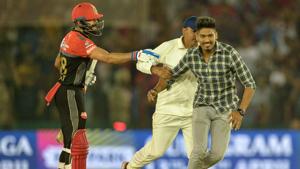 A fan (R) of Royal Challengers Bangalore (RCB) cricketer Virat Kohli (L) is pursued by a security official (C).(AFP) A fan (R) of Royal Challengers Bangalore (RCB) cricketer Virat Kohli (L) is pursued by a security official (C).(AFP)