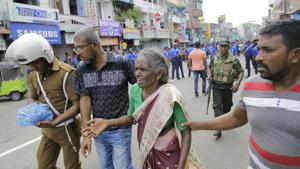 Sri Lankan elderly woman is helped near St. Anthony's Shrine after a blast in Colombo on Sunday after the multiple explosions that rocket the city.(AP) Sri Lankan elderly woman is helped near St. Anthony's Shrine after a blast in Colombo on Sunday after the multiple explosions that rocket the city.(AP)