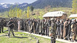 Security personnel stand guard as voters wait in queue to cast their votes outside a polling station at Gulzarabad in Kulgam district on April 29.(ANI file photo)