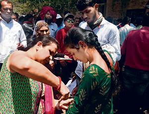 A parent cuts off her daughter’s sleeve, as per the dress code, before she enters the examination centre.(HT photo)