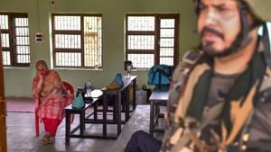A security personnel stands guard as poll officials wait for voters at a polling station in Anantnag district of Jammu and Kashmir on April 23.(PTI)