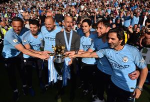 Manchester City's Spanish manager Pep Guardiola (C) and his back-room staff pose with the Premier League trophy after their 4-1 victory in the English Premier League football match between Brighton and Hove Albion and Manchester City at the American Express Community Stadium in Brighton, southern England on May 12, 2019. Manchester City's Spanish manager Pep Guardiola (C) and his back-room staff pose with the Premier League trophy after their 4-1 victory in the English Premier League football match between Brighton and Hove Albion and Manchester City at the American Express Community Stadium in Brighton, southern England on May 12, 2019.