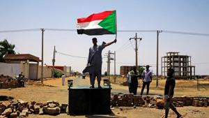 A Sudanese protester holds a national flag as he stands on a barricade along a street, demanding that the country's Transitional Military Council hand over power to civilians, in Khartoum, Sudan.(Reuters Photo) A Sudanese protester holds a national flag as he stands on a barricade along a street, demanding that the country's Transitional Military Council hand over power to civilians, in Khartoum, Sudan.(Reuters Photo)