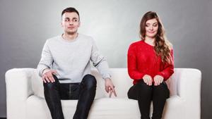 Shy woman and man. Guy sitting near attractive young woman on sofa and making hand gesture walking with finger to girl(Getty Images/iStockphoto)