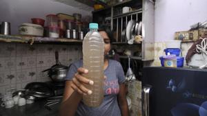 A resident of Noida’s Sector 12 holds up a bottle with dirty water. The residents’ body has written to the Noida authority complaining about the poor quality of water.(Sunil Ghosh / HT PHoto)
