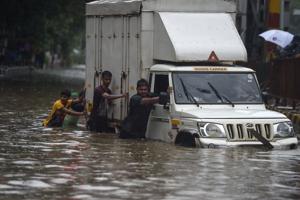 Indian men push a truck along a flooded street after heavy rain showers in Mumbai on July 1, 2019.(AFP) Indian men push a truck along a flooded street after heavy rain showers in Mumbai on July 1, 2019.(AFP)