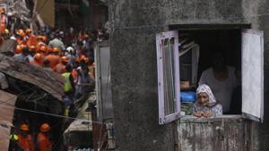 A woman looks from a window as rescuers work at the site of a building that collapsed in Mumbai on Tuesday, July 16. A four-story residential building collapsed in a crowded neighborhood in Mumbai, India's financial and entertainment capital, and several people were feared trapped in the rubble, an official said.(Photo: AP) A woman looks from a window as rescuers work at the site of a building that collapsed in Mumbai on Tuesday, July 16. A four-story residential building collapsed in a crowded neighborhood in Mumbai, India's financial and entertainment capital, and several people were feared trapped in the rubble, an official said.(Photo: AP)