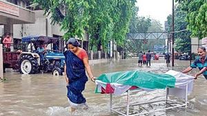 Workers push a gurney carrying a dead body as they wade through the waterlogged campus of a Vadodara hospital.(AFP) Workers push a gurney carrying a dead body as they wade through the waterlogged campus of a Vadodara hospital.(AFP)