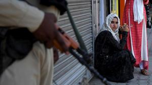 A woman sits as CRPF personnel stand guard in Srinagar, August 4, 2019(ANI Photo) A woman sits as CRPF personnel stand guard in Srinagar, August 4, 2019(ANI Photo)