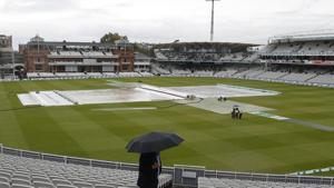 A spectator looks at the field of play that is covered to protect the wicket from rain.(AP) A spectator looks at the field of play that is covered to protect the wicket from rain.(AP)