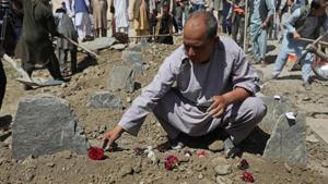 An Afghan man put flowers on a grave of his relative during a mass funeral after a suicide bomb blast at a wedding in Kabul, Afghanistan .(Reuters Photo) An Afghan man put flowers on a grave of his relative during a mass funeral after a suicide bomb blast at a wedding in Kabul, Afghanistan .(Reuters Photo)