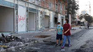 People wearing masks walk past damaged shops, a day after protests targeting the government over an economic crisis in Beirut, Lebanon.(Reuters photo) People wearing masks walk past damaged shops, a day after protests targeting the government over an economic crisis in Beirut, Lebanon.(Reuters photo)