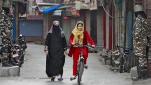 A Kashmir girl rides her bike past security personnel, Srinagar, October 30, 2019(REUTERS) A Kashmir girl rides her bike past security personnel, Srinagar, October 30, 2019(REUTERS)