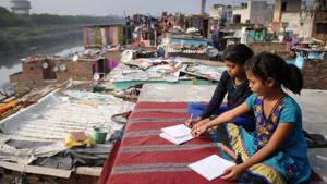 Poonam and Kiran, daughters of a cycle rickshaw puller, do their home work on the rooftop of their shanty in Noida.(Burhaan Kinu/HT PHOTO) Poonam and Kiran, daughters of a cycle rickshaw puller, do their home work on the rooftop of their shanty in Noida.(Burhaan Kinu/HT PHOTO)