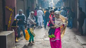 A woman carries a child as she walks past the spot where fire broke out in a factory in New Delhi on Sunday.(PTI Photo) A woman carries a child as she walks past the spot where fire broke out in a factory in New Delhi on Sunday.(PTI Photo)