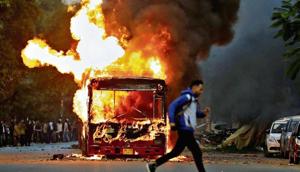 A man runs past a bus that was set on fire by protesters near New Friends Colony in New Delhi on Sunday.(Reuters) A man runs past a bus that was set on fire by protesters near New Friends Colony in New Delhi on Sunday.(Reuters)