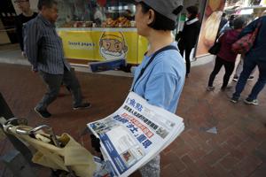 A vendor gives out copies of newspaper with a headlines of A vendor gives out copies of newspaper with a headlines of