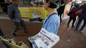 A vendor gives out copies of newspaper with a headlines of A vendor gives out copies of newspaper with a headlines of