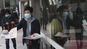 A woman wearing a protective face mask delivers a leaflet on coronavirus in Wuhan, in Hong Kong on Friday. China broadened its unprecedented, open-ended lockdowns to encompass around 25 million people to try to contain a new virus that has sickened hundreds.(AP Photo) A woman wearing a protective face mask delivers a leaflet on coronavirus in Wuhan, in Hong Kong on Friday. China broadened its unprecedented, open-ended lockdowns to encompass around 25 million people to try to contain a new virus that has sickened hundreds.(AP Photo)