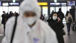 A woman wears a mask as an employee works to prevent a new coronavirus.(AP Photo) A woman wears a mask as an employee works to prevent a new coronavirus.(AP Photo)