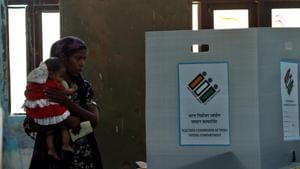 A voter, carrying her son, casts her vote during the repolling at Daryaganj, in Delhi.(Amal KS/HT PHOTO)