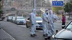 Officials in protective suits gathered on a street in Wuhan.The WHO declared a global emergency over the new coronavirus.(AFP Photo)