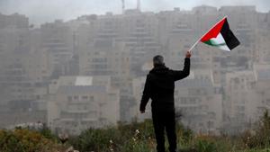 A demonstrator holds a Palestinian flag as the Jewish settlement of Modiin is seen in the background, during a protest against the U.S. President Donald Trump's Middle East peace plan, in the village of Bilin in the Israeli-occupied West Bank February 7, 2020.(REUTERS) A demonstrator holds a Palestinian flag as the Jewish settlement of Modiin is seen in the background, during a protest against the U.S. President Donald Trump's Middle East peace plan, in the village of Bilin in the Israeli-occupied West Bank February 7, 2020.(REUTERS)