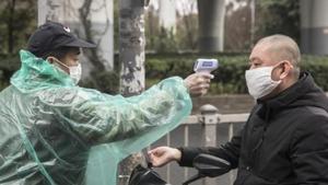 A security guard takes the temperature of a man wearing a protective mask at an entrance to a fresh produce market in Shanghai, China.(Bloomberg) A security guard takes the temperature of a man wearing a protective mask at an entrance to a fresh produce market in Shanghai, China.(Bloomberg)