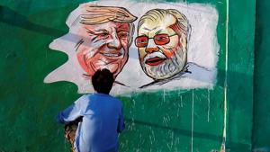 A man applies finishing touches to paintings of U.S. President Donald Trump and Prime Minister Narendra Modi on a wall as part of a beautification along a route that the two leaders will be taking during Trump's upcoming visit, in Ahmedabad, February 17, 2020.(REUTERS)