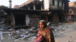 A woman walks past a damaged building in northeast Delhi’s Brahmpuri, on Wednesday.(Amal KS / HT Photo)
