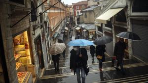 People shelter against the rain with umbrellas as they walk along the Rialto bridge on a rainy day in Venice, on Sunday. In northern Italy, the virus Covid-19 is taking a deep social toll, curtailing the usual opportunities to meet.(AP Photo) People shelter against the rain with umbrellas as they walk along the Rialto bridge on a rainy day in Venice, on Sunday. In northern Italy, the virus Covid-19 is taking a deep social toll, curtailing the usual opportunities to meet.(AP Photo)