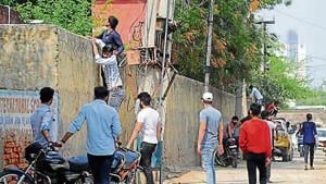 Youths try to scale the wall of a government school in Gurugram on Tuesday.(HT) Youths try to scale the wall of a government school in Gurugram on Tuesday.(HT)