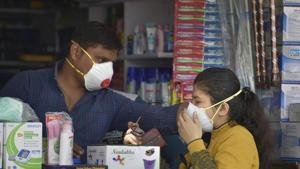 A salesmen at a chemist shop in New Delhi helps a buyer wear her protective mask, in wake of the deadly coronavirus, on Wednesday.(PTI Photo) A salesmen at a chemist shop in New Delhi helps a buyer wear her protective mask, in wake of the deadly coronavirus, on Wednesday.(PTI Photo)
